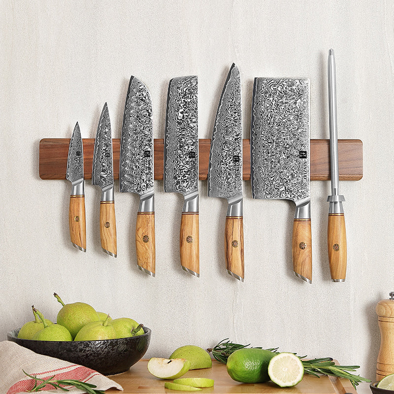 Magneetstrip met diverse messen, lichte muur en fruit op achtergrond
