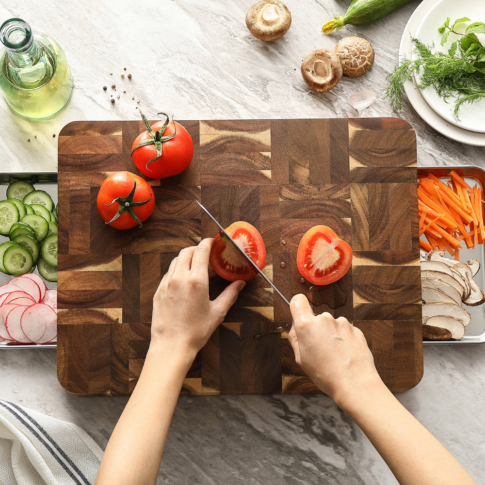 Kopshouten snijplank acacia met verse ingrediënten en snijdende hand