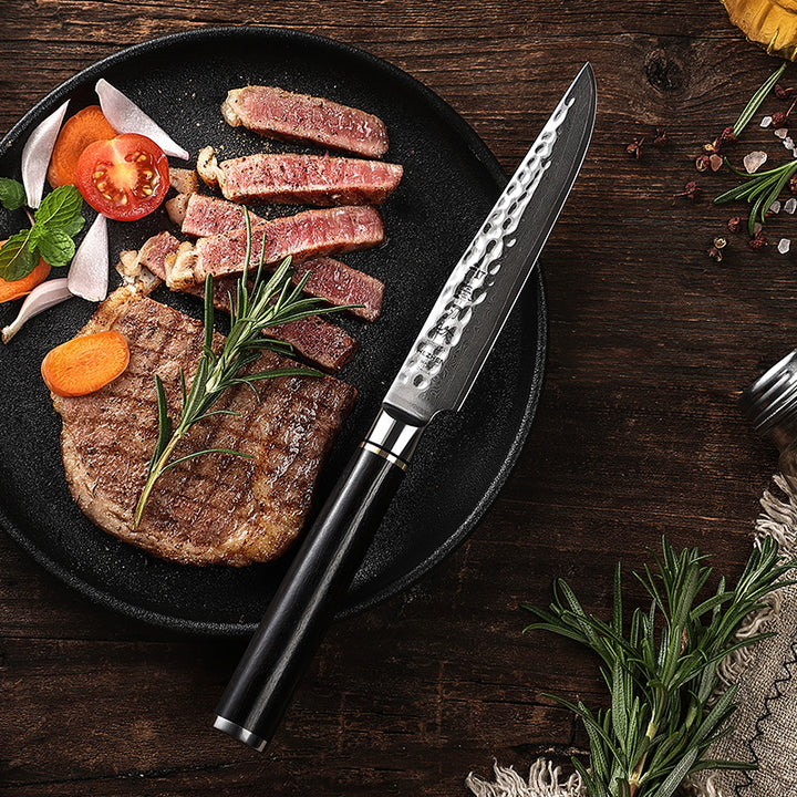 Hezhen B1Z Classic steakmes naast steak en garnituren op zwart bord