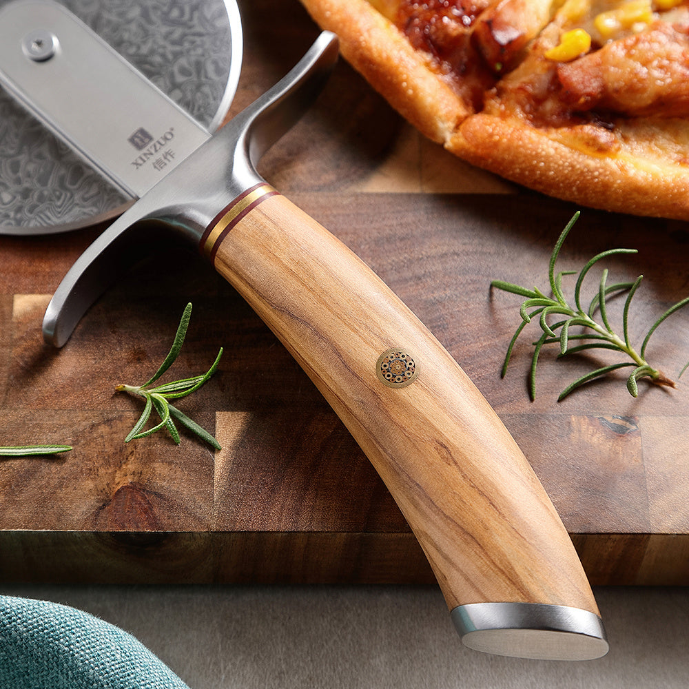 Olijfhouten handvat van de B37 Lan pizzasnijder op een plank met pizza