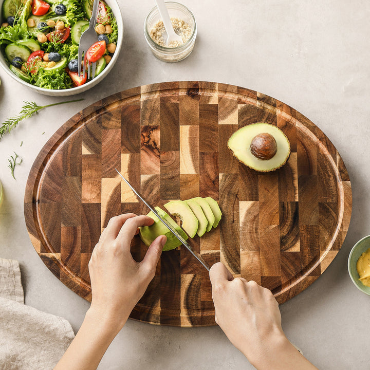 Hand snijdt avocado op acacia snijplank