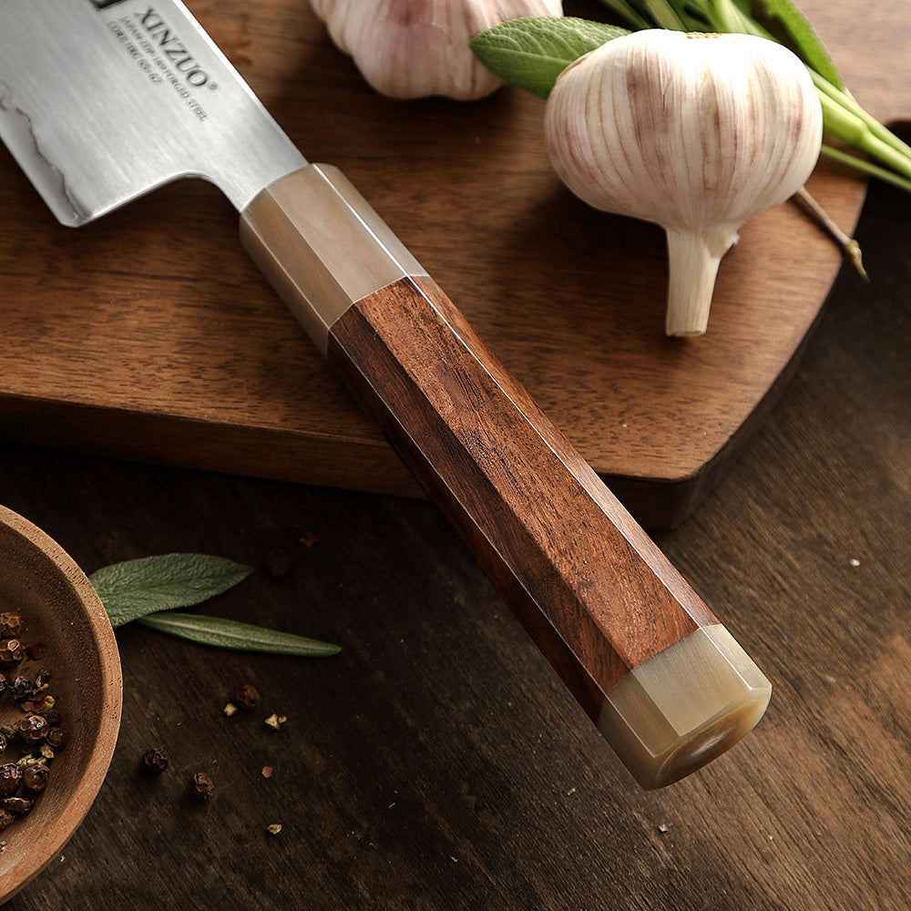 Houten handvat van het XinZuo X05Z Zhen santokumes met knoflook op de achtergrond