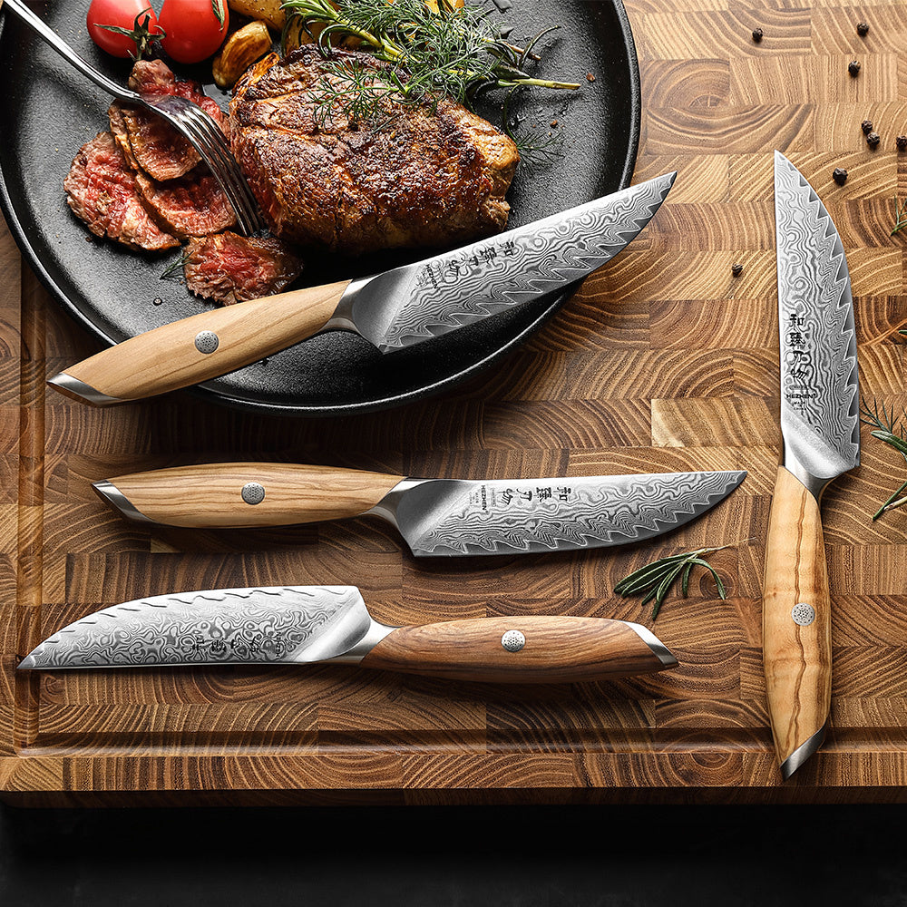 Hezhen X01 Flagship steakmessenset naast gegrild vlees en tomaten