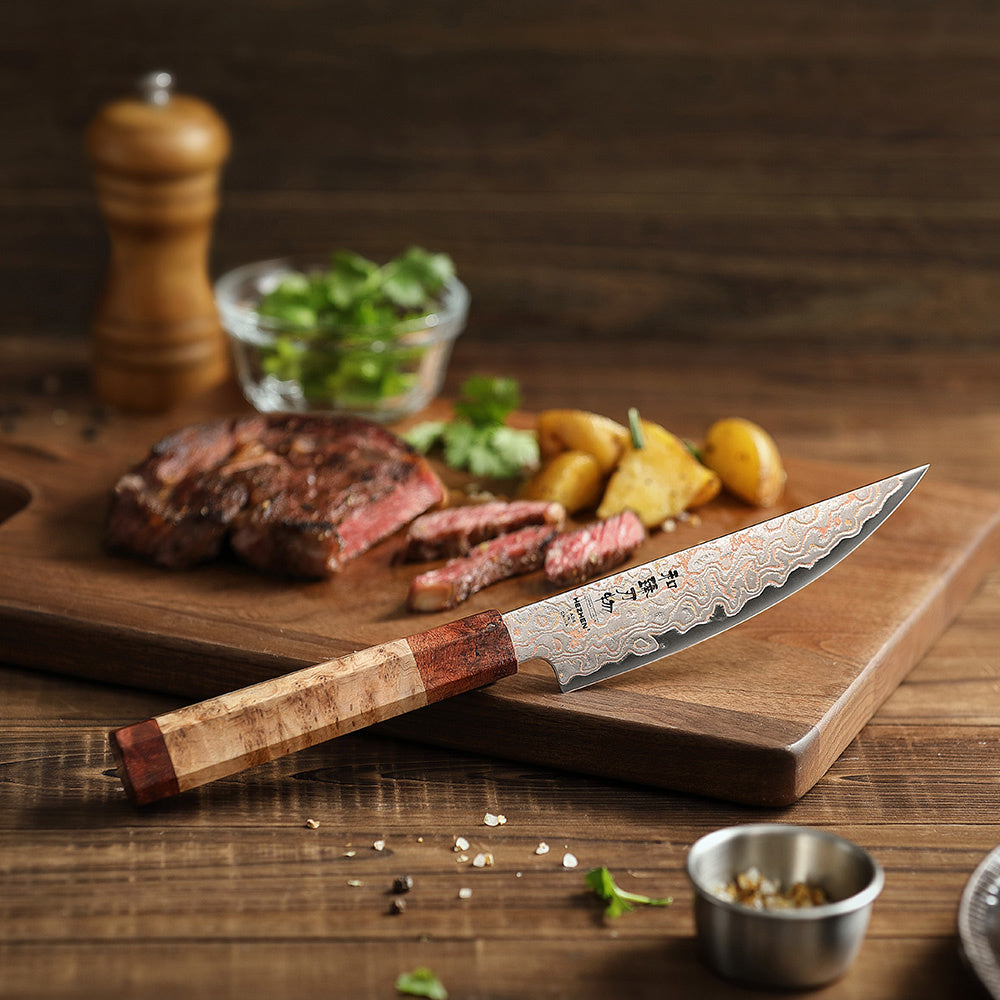 Hezhen X05C steakmes op snijplank met vlees en bijgerechten