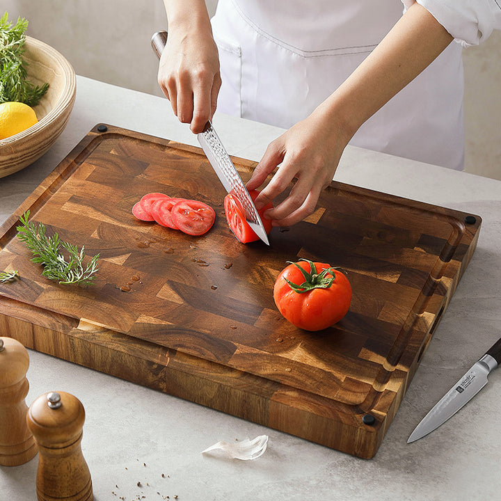 Kopshouten snijplank acacia met hand snijdt tomaten