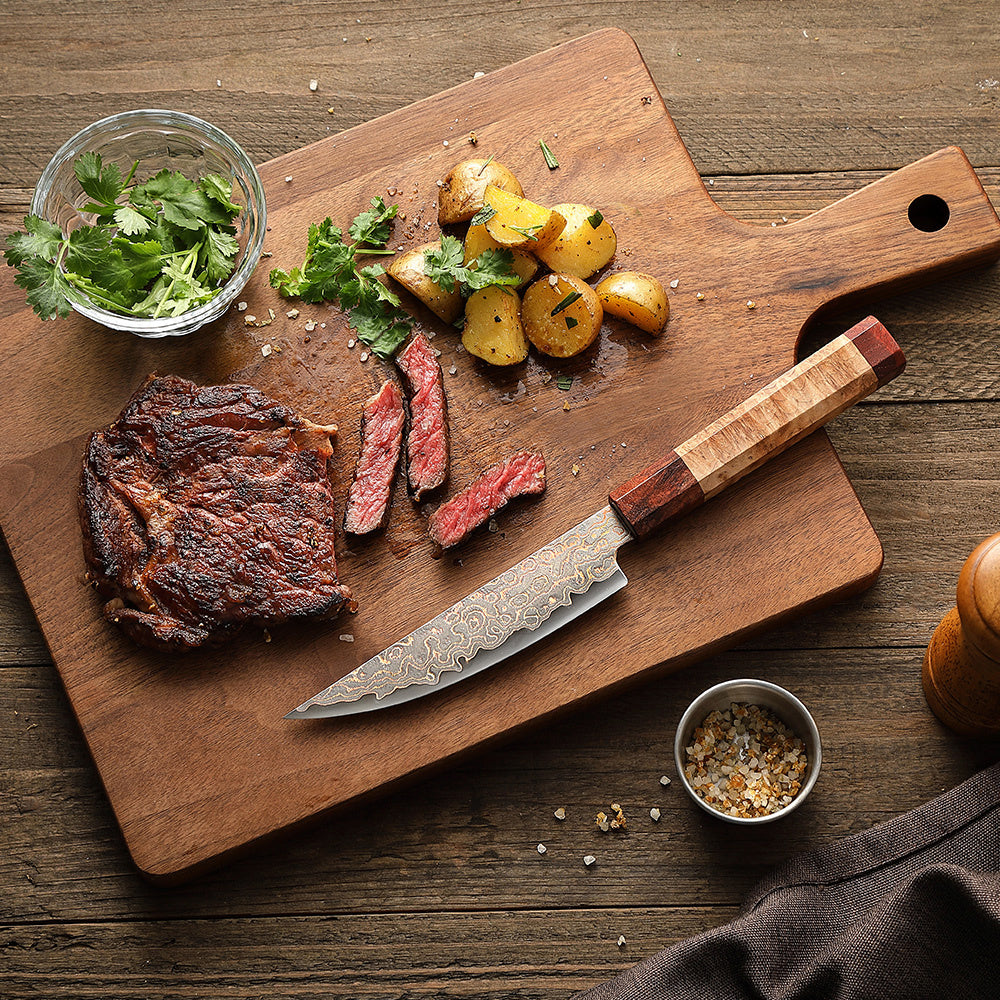 Hezhen X05C steakmes naast gegrild vlees en kruiden op plank