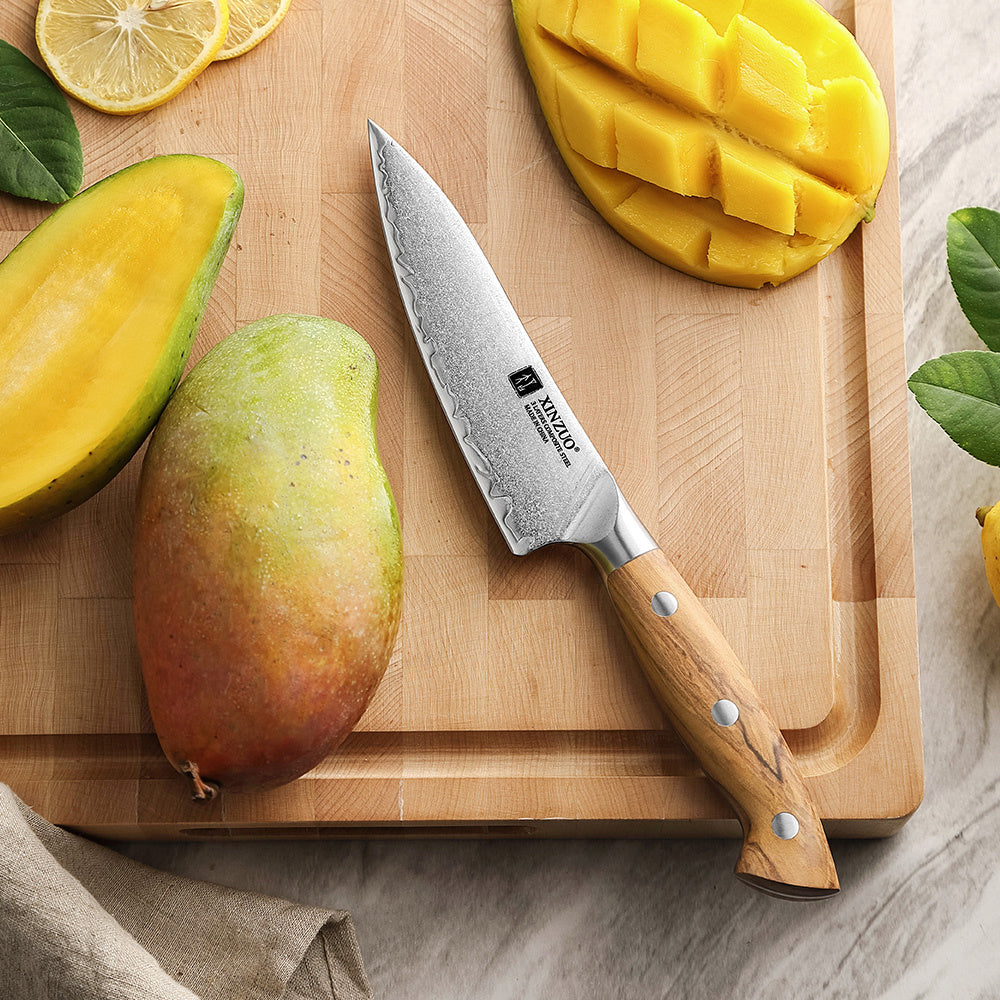 X02O Pin groentemes naast gesneden en hele mango op plank