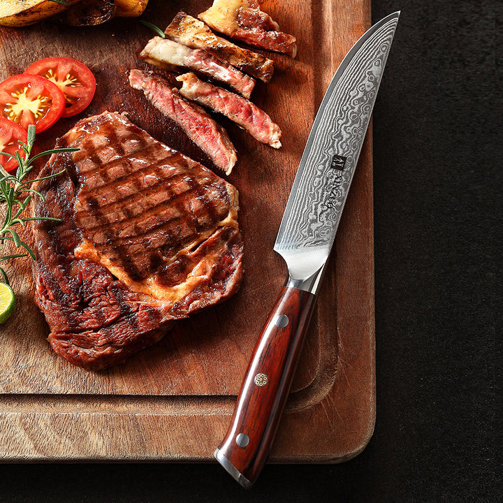 B13R Yu steakmes naast vlees en tomaat op een plank