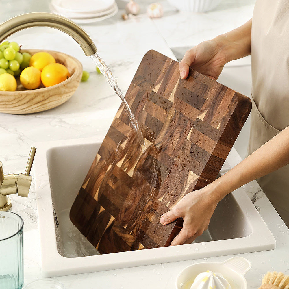 Kopshouten snijplank acacia onder stromend water boven gootsteen