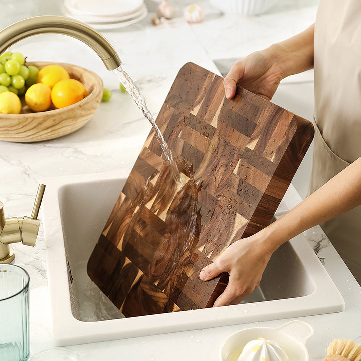 Kopshouten snijplank acacia onder stromend water boven gootsteen