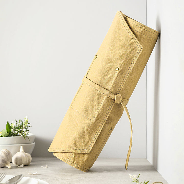 Opgerolde gele canvas messentas hangt aan muur
