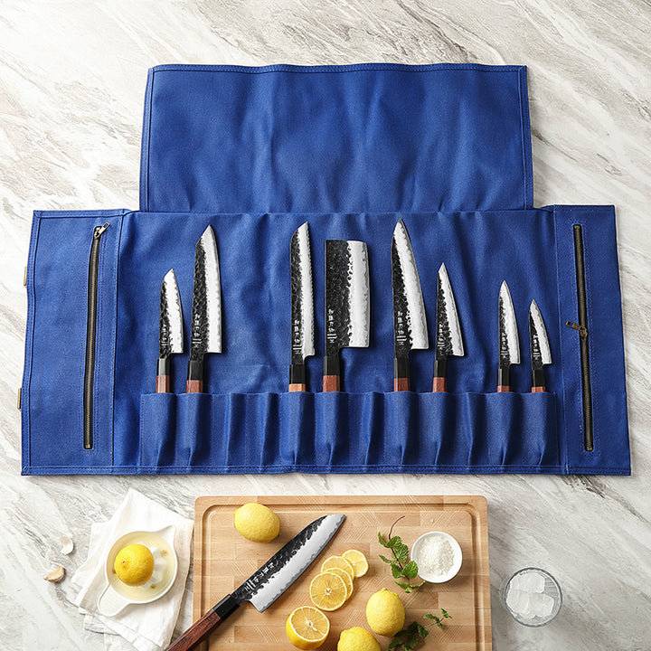 Open blauwe messentas met acht messen, op lichte ondergrond met ingrediënten