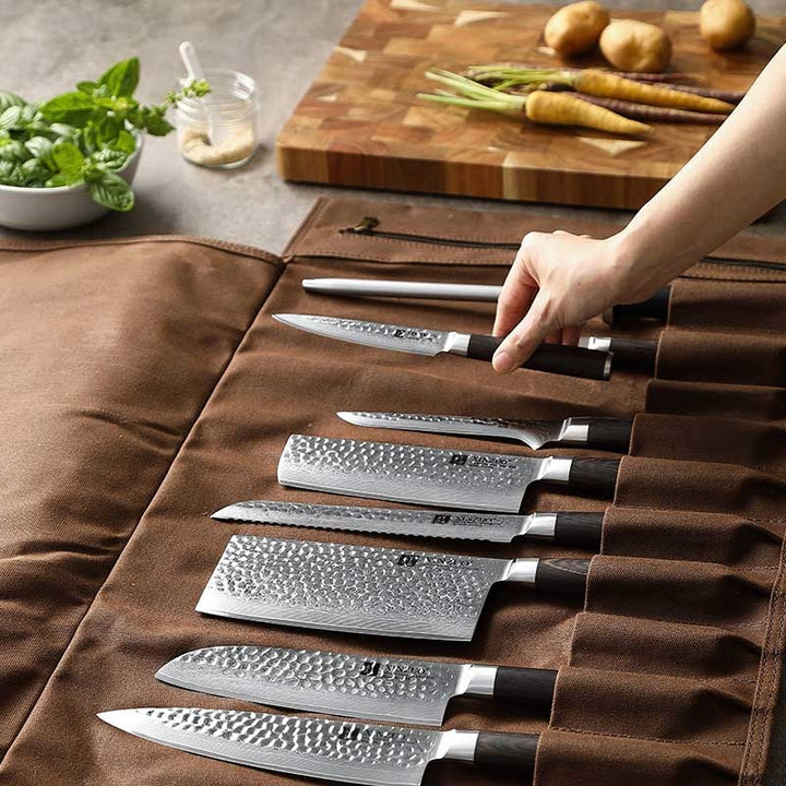 Hand pakt mes uit bruine messentas met koksmes en santoku zichtbaar