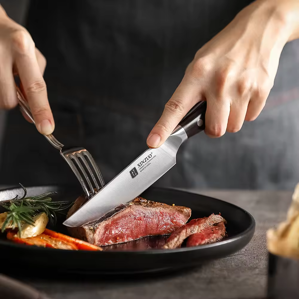 XinZuo steakmes snijdt steak op een zwart bord met garnituur