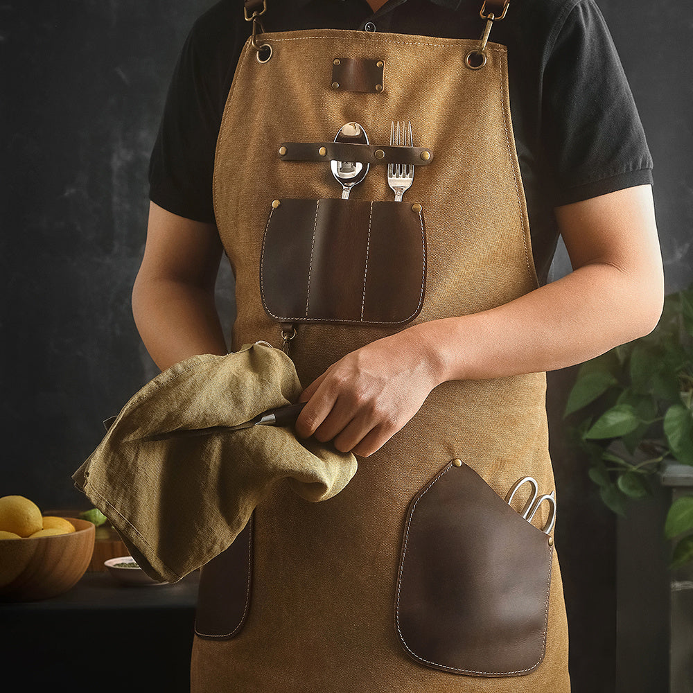 Bruin keukenschort met zakken, bestek en doek in de hand