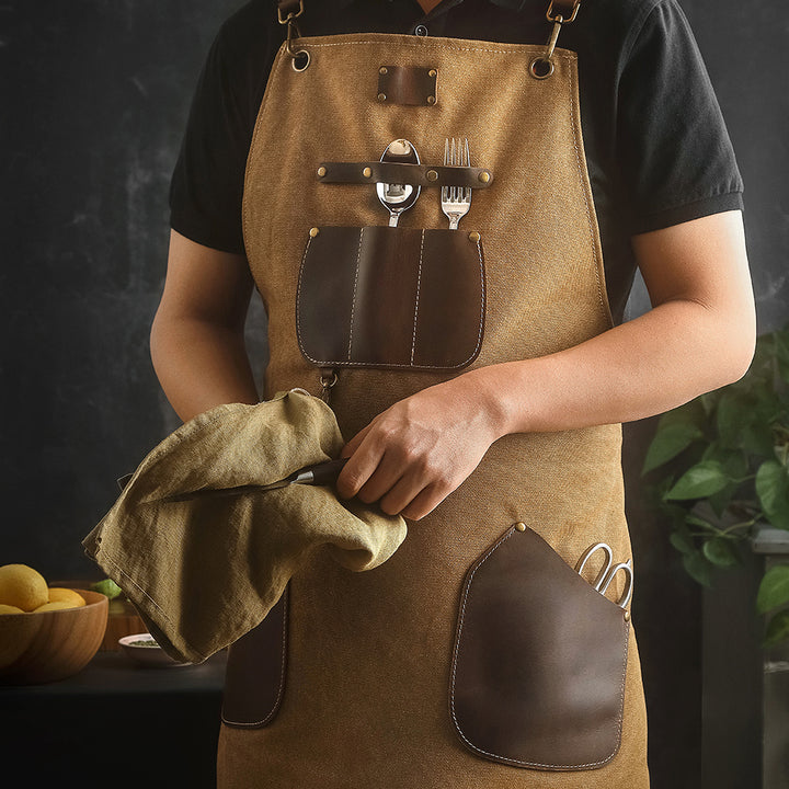 Bruin keukenschort met zakken, bestek en doek in de hand