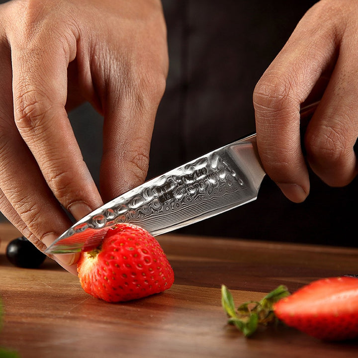 B13D Yu schilmes snijdt een aardbei, met damastpatroon zichtbaar