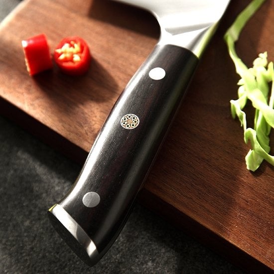 Handvat van de XinZuo B13S Yu cleaver met snijplank op de achtergrond