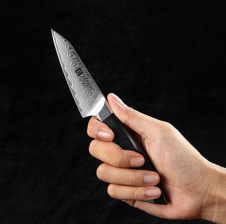 XinZuo B32 Feng schilmes in een hand tegen donkere achtergrond